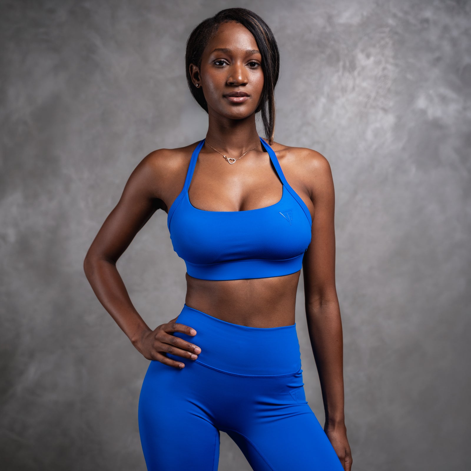 Woman wearing a blue sports bra and leggings against a gray background